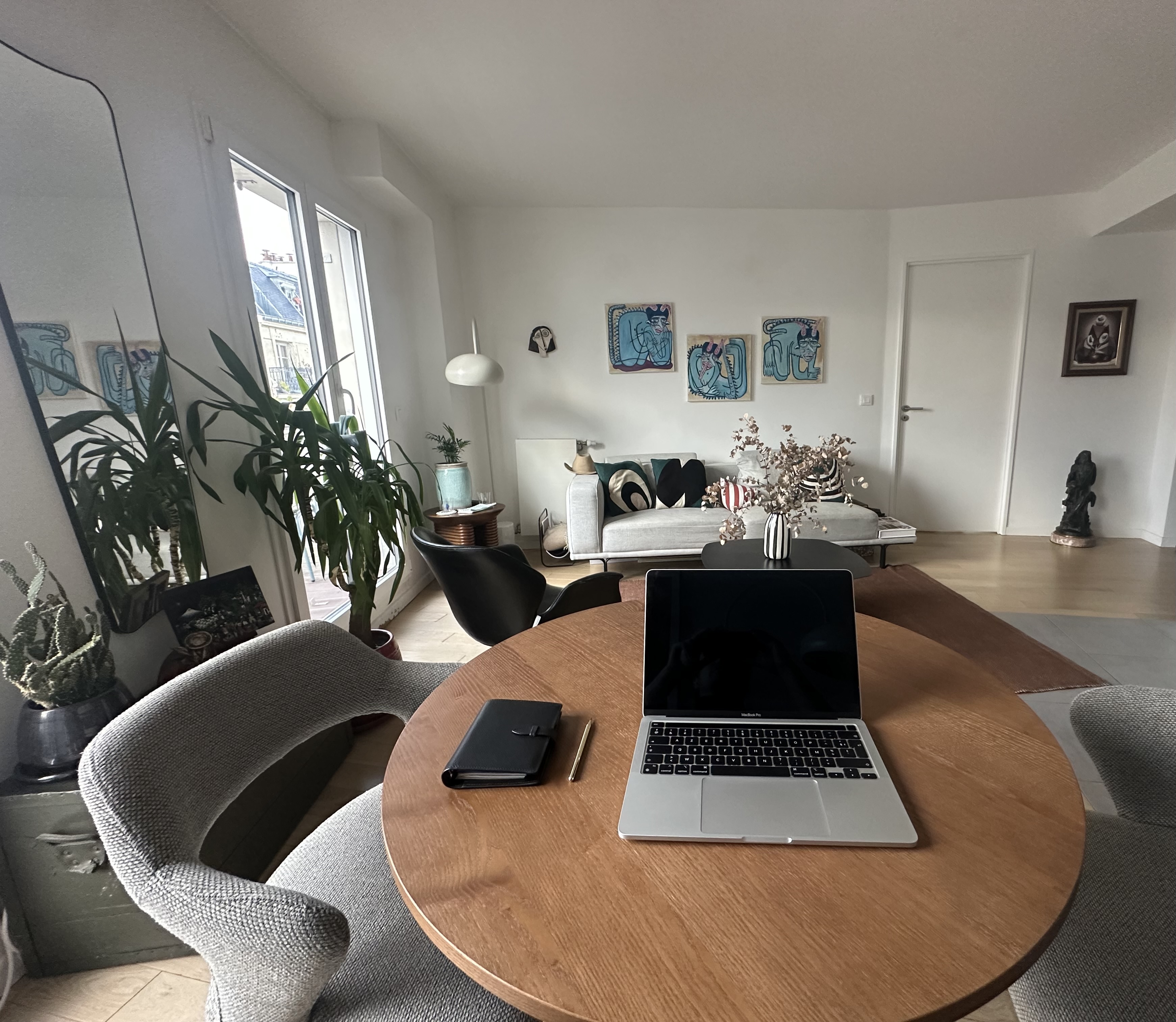 Le bureau de Romain Bigache : table ronde, MacBook, carnet et fauteuils